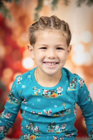 Portrait with turquoise winter-themed shirt against festive bokeh background.