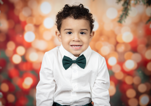 Formal portrait with white dress shirt and bow tie against red and gold bokeh background.