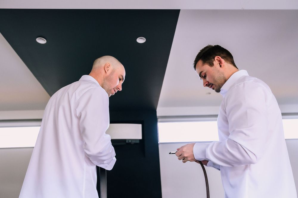 Two people in white dress shirts looking at a device.