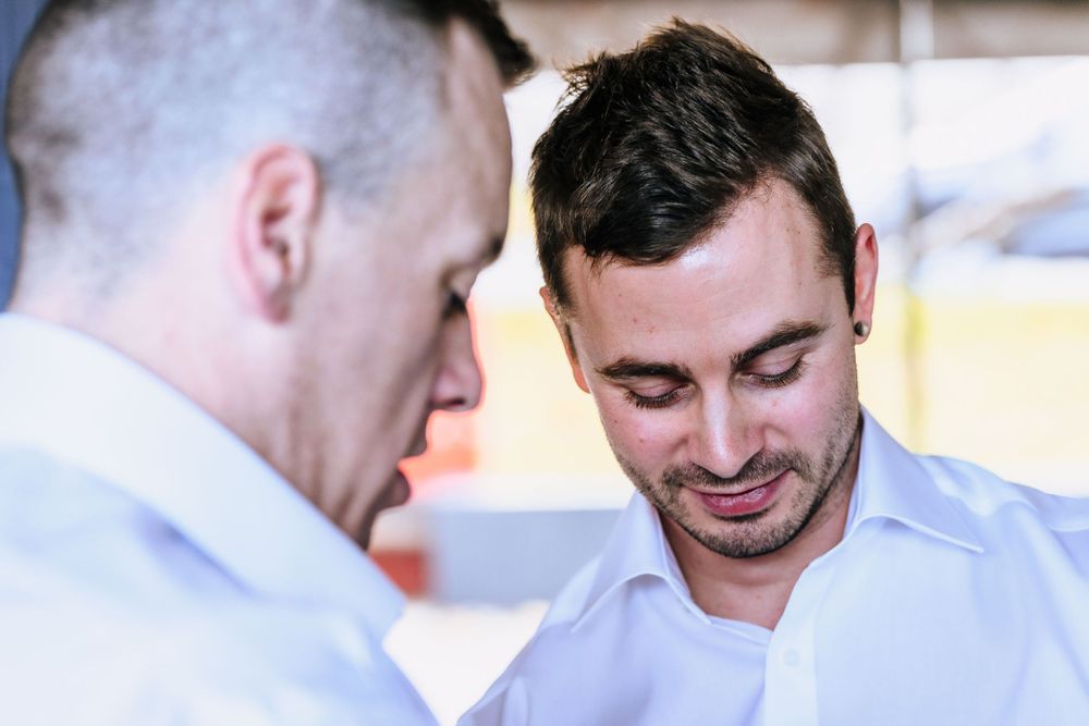 Two people in white shirts engaged in conversation indoors.