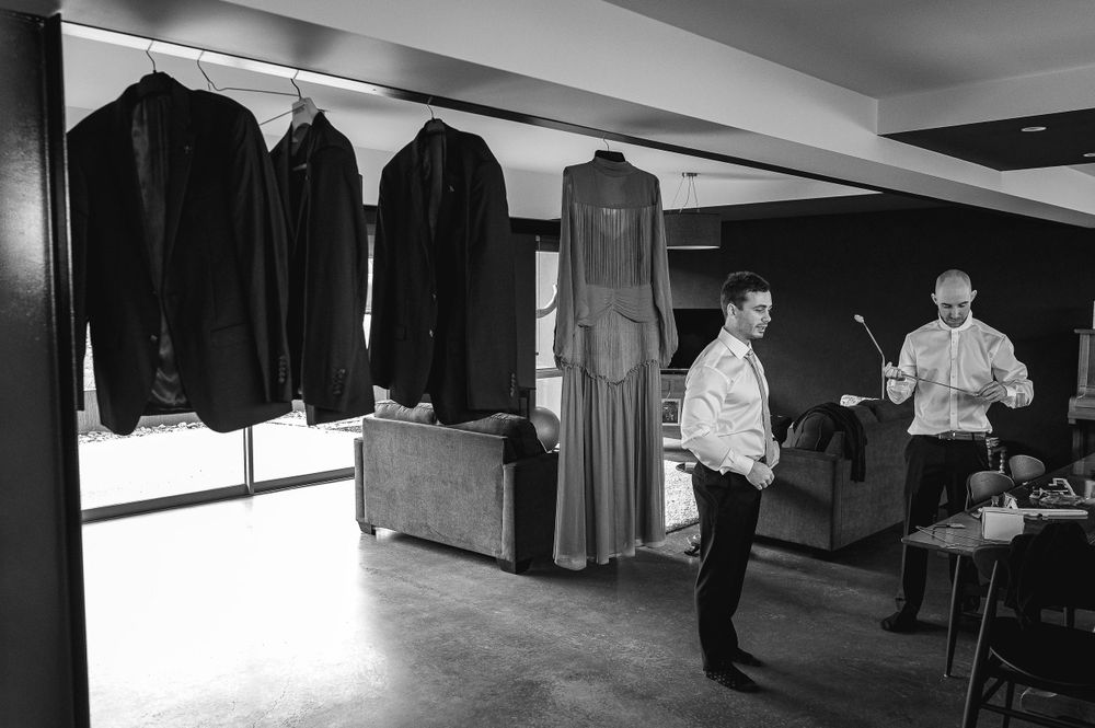 Black and white photo of formal wear hanging with people in background.