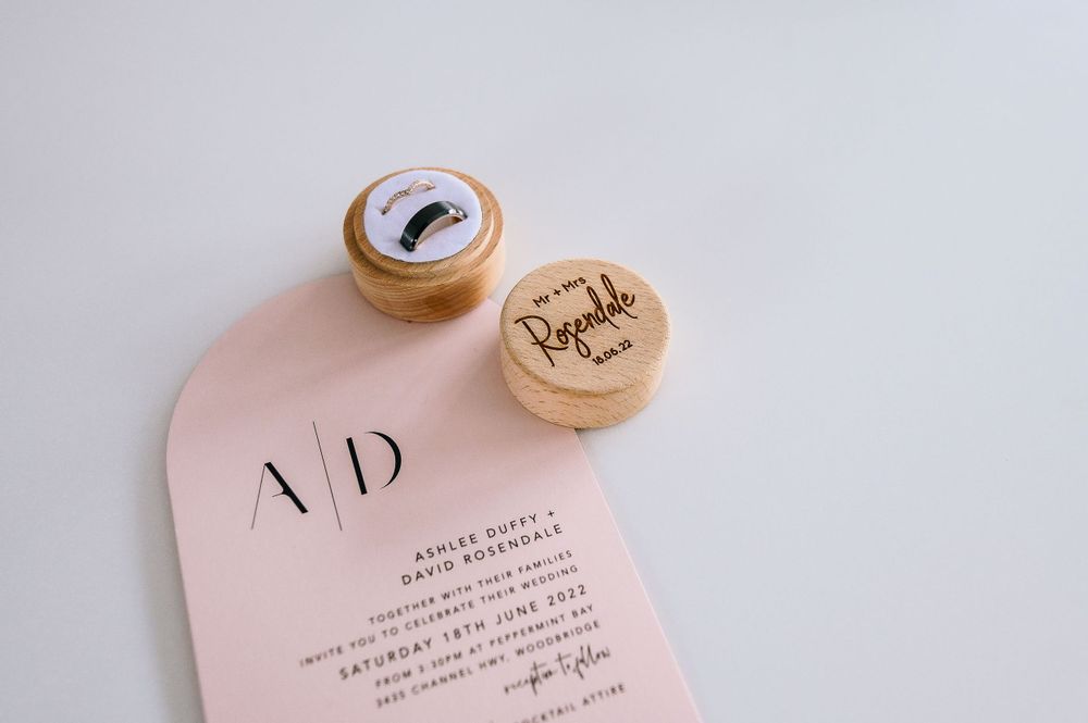 Wedding invitation and wooden cork details on pink background.