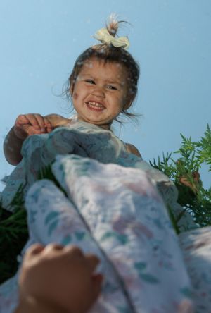 Joyful candid moment shot from below against a blue sky with greenery visible.