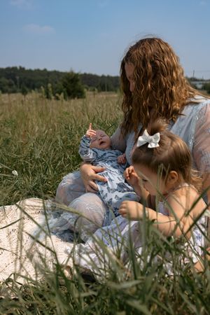 Peaceful summer day scene of people relaxing together on a blanket in tall grass meadow.