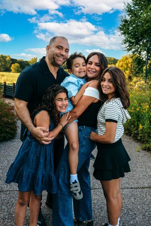 A family shares joyful moments together on a sunny day with yellow wildflowers and blue sky in the background.