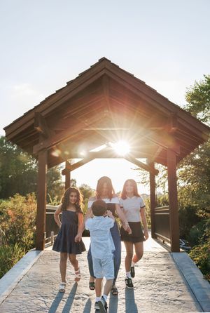 A group of friends walking on a covered bridge path in golden sunlight during sunset.