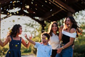 A wedding party dances joyfully outdoors during a celebration with golden sunlight filtering through the trees.