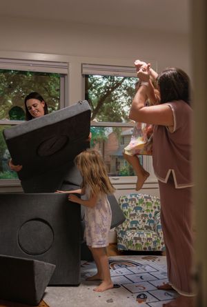 A series of four connected images showing someone playfully throwing a black coat in a living room setting.