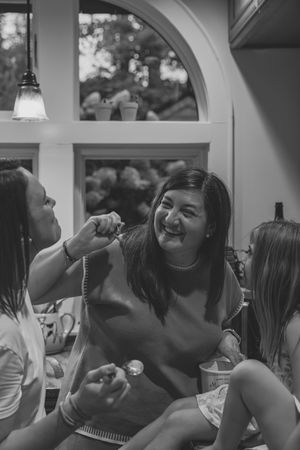 A group of people laughing joyfully together during a social gathering in black and white.