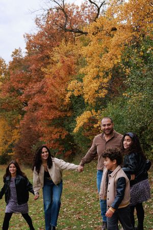 A group plays and poses together against a backdrop of vibrant autumn trees with orange and red foliage.