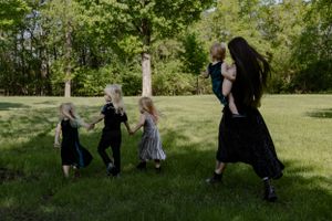 A group enjoys a playful moment dancing together in a sunny green field.