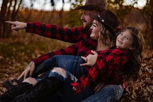 Playful moment captured in autumn setting with matching plaid outfits.