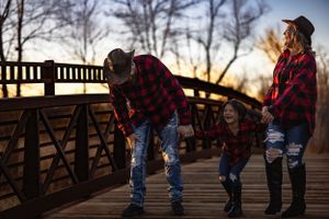 Group in matching plaid shirts on wooden bridge at sunset.