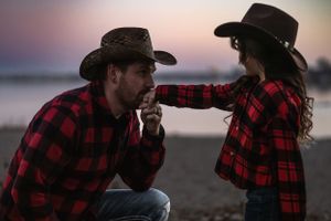 A touching moment between two people wearing matching buffalo plaid shirts at sunset.