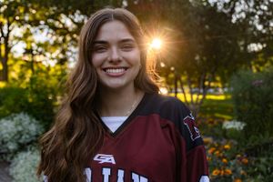 Portrait of a student athlete in a maroon jersey with golden sunset lighting.
