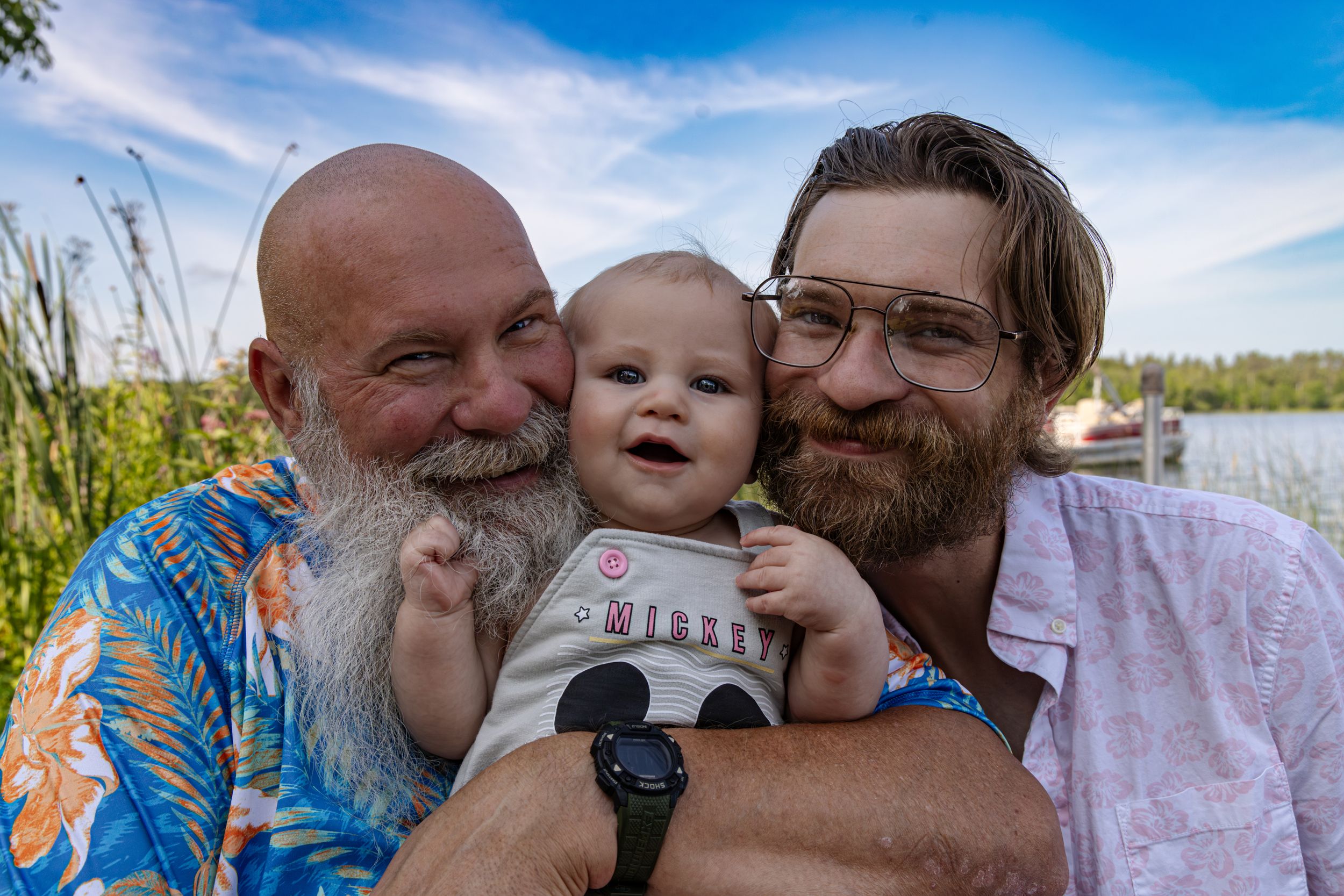 Three generations share a tender moment together outdoors near a lake.