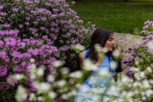 Dreamy portrait of someone in a blue dress among blooming purple and white flowers.