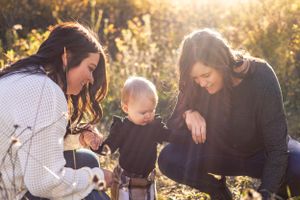 Three people gather outdoors during golden hour sunlight.
