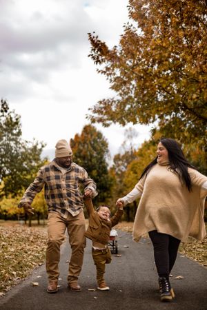 Family walking together on path surrounded by golden fall foliage.