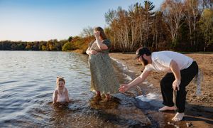 Maternity photo of mom, daughter and dad playing at the lake
