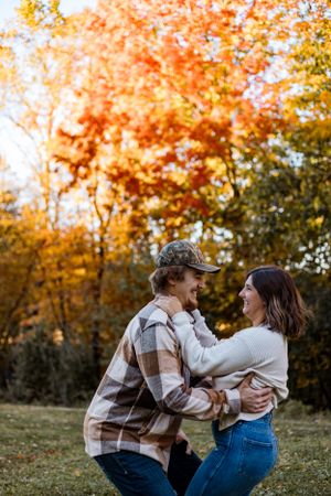 Couple sharing romantic moment against backdrop of golden autumn trees.