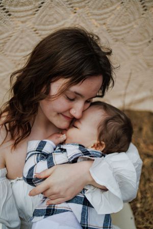 An intimate moment between parent and baby against a cream-colored backdrop.