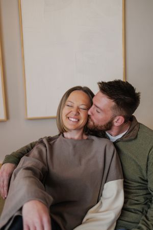 A couple sharing an intimate moment on the couch while wearing cozy sweaters.