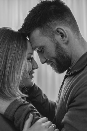 Intimate black and white portrait of a couple in a tender embrace.