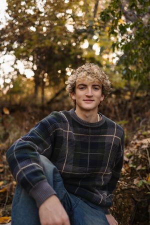 Person wearing plaid sweater sitting outdoors during autumn golden hour.