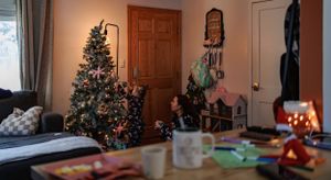 Decorated Christmas tree and holiday decor in corner of warmly lit living room.