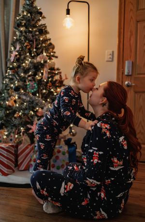 Matching holiday pajamas shared moment by decorated Christmas tree in cozy home setting.