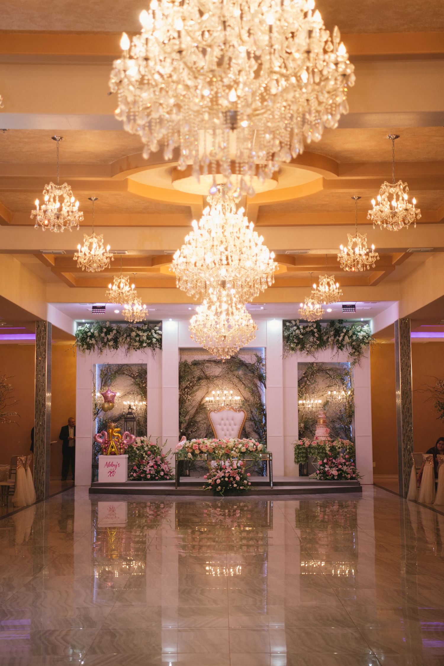Elegant ballroom entrance with crystal chandeliers and floral arch display creating a luxurious wedding venue atmosphere.
