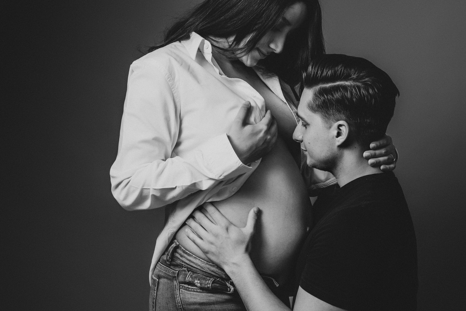 A black and white photo collage showing intimate moments between expecting parents embracing her bump in a romantic intimate poses.
