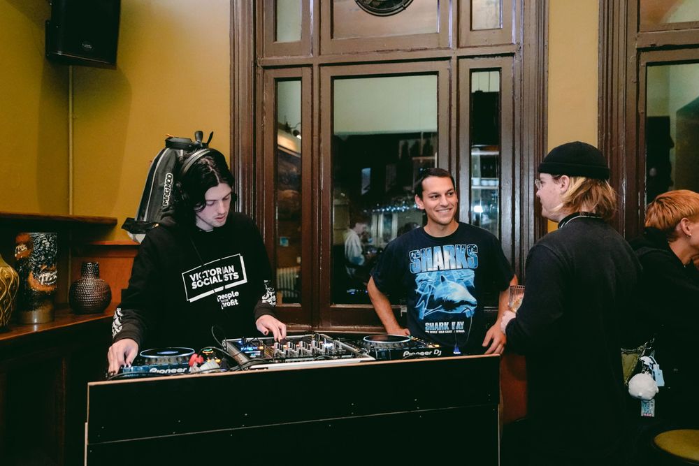 DJs operating equipment at a mixing console during an event.