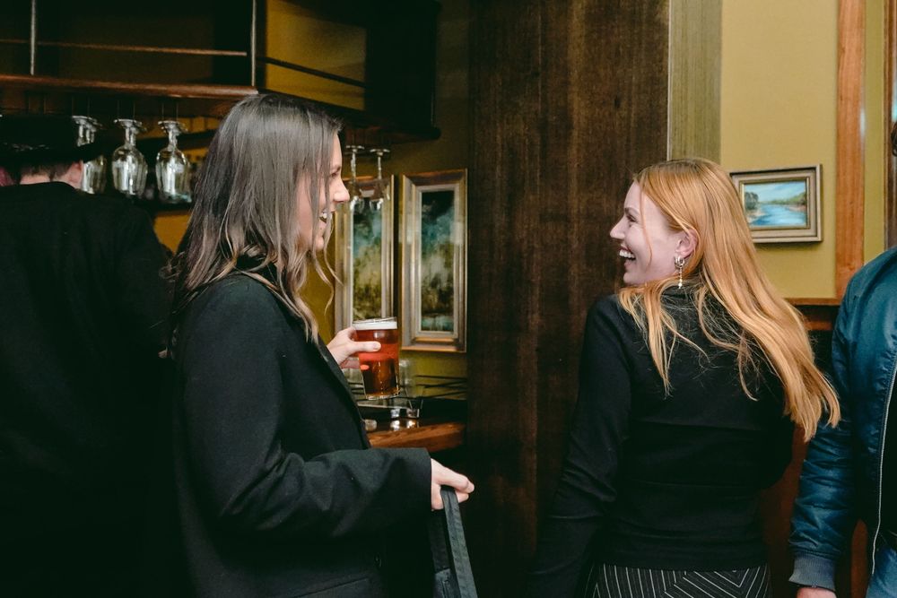 Social gathering in dimly lit bar with people engaged in conversation.