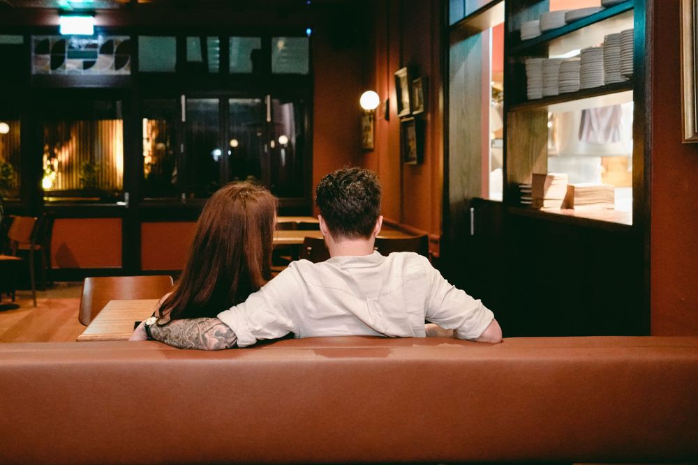 A couple watching TV together in a dimly lit room with leather seating.