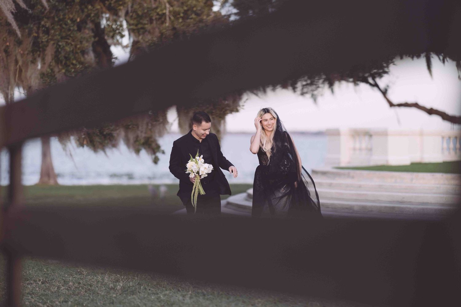 A couple shares a romantic moment under moody lighting with trees in the background.