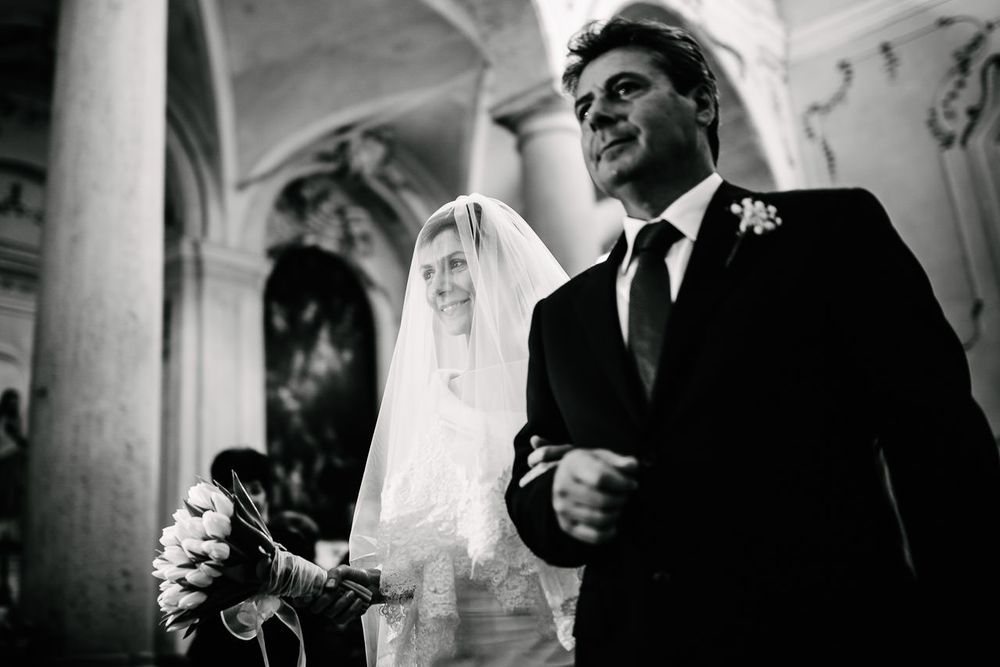 Classic black and white wedding ceremony moment in an ornate church setting.