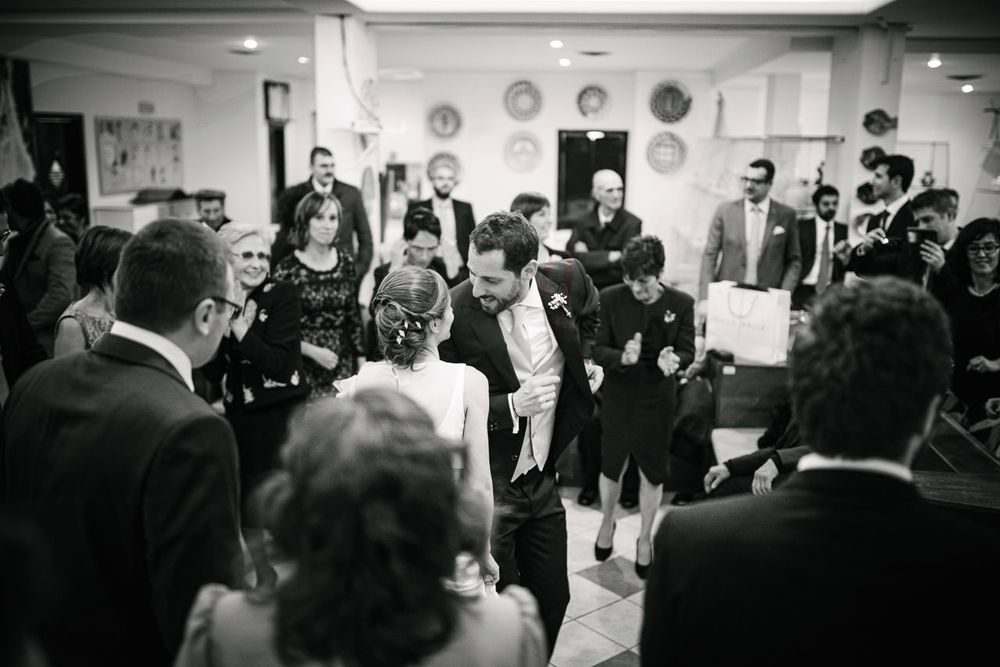 Black and white panoramic view of wedding reception with guests mingling.