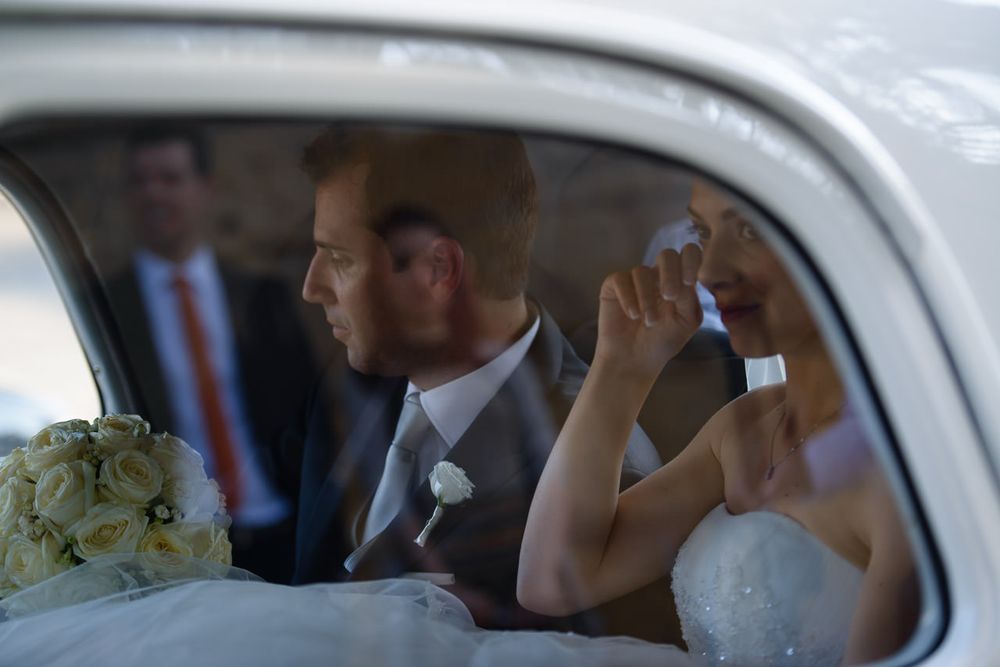 Wedding party waving from inside a classic car.