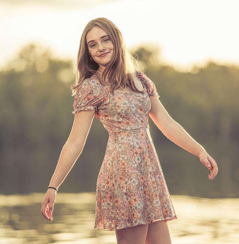 Sunset portrait in floral dress with golden backlight and natural scenery.