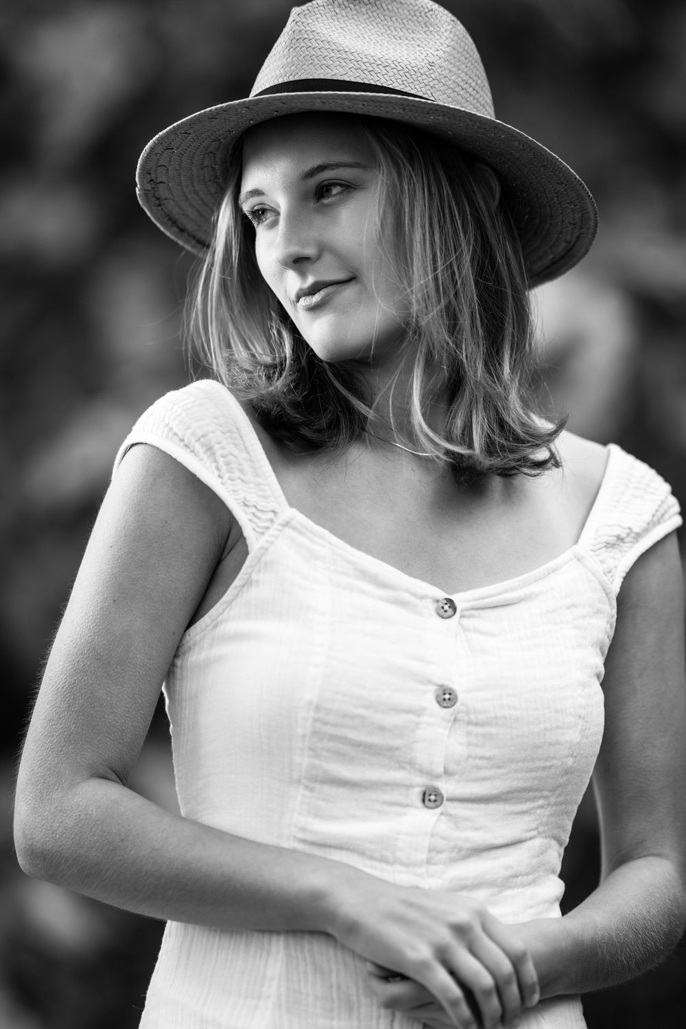 Vintage-style portrait featuring a summer hat and white button-up dress.