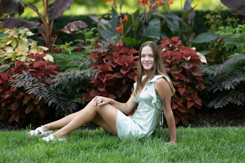 Summer portrait on grass with white dress and colorful garden background.
