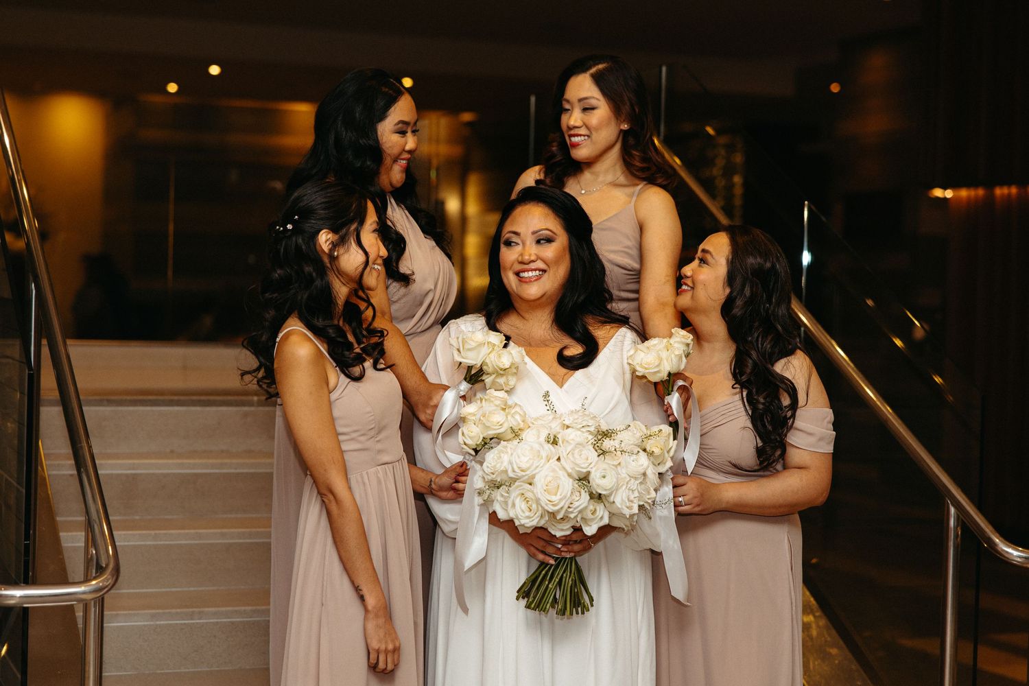 Wedding party members share joyful moments in an elegant indoor setting.