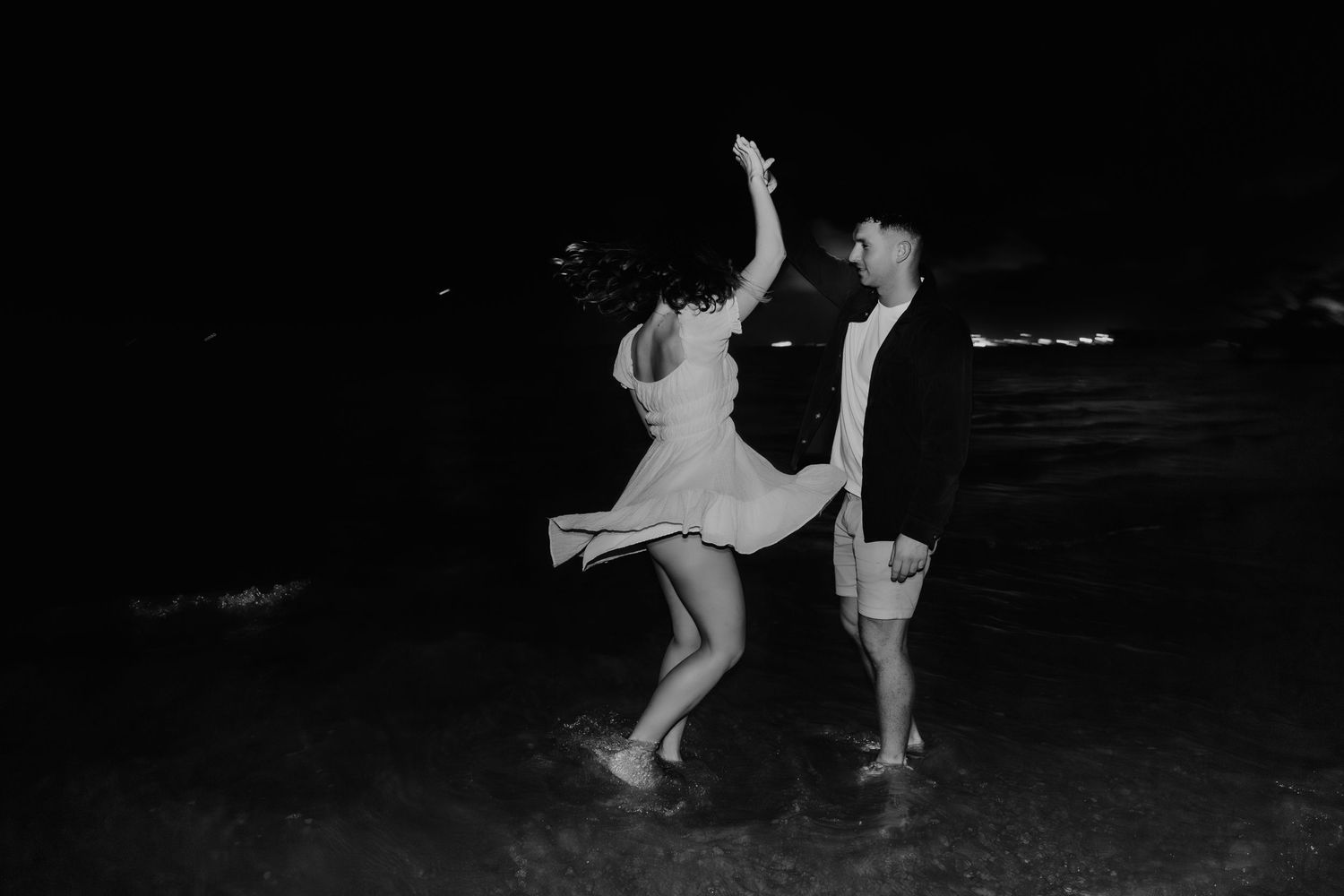 A black and white photograph shows two figure skaters performing a graceful lift on ice.