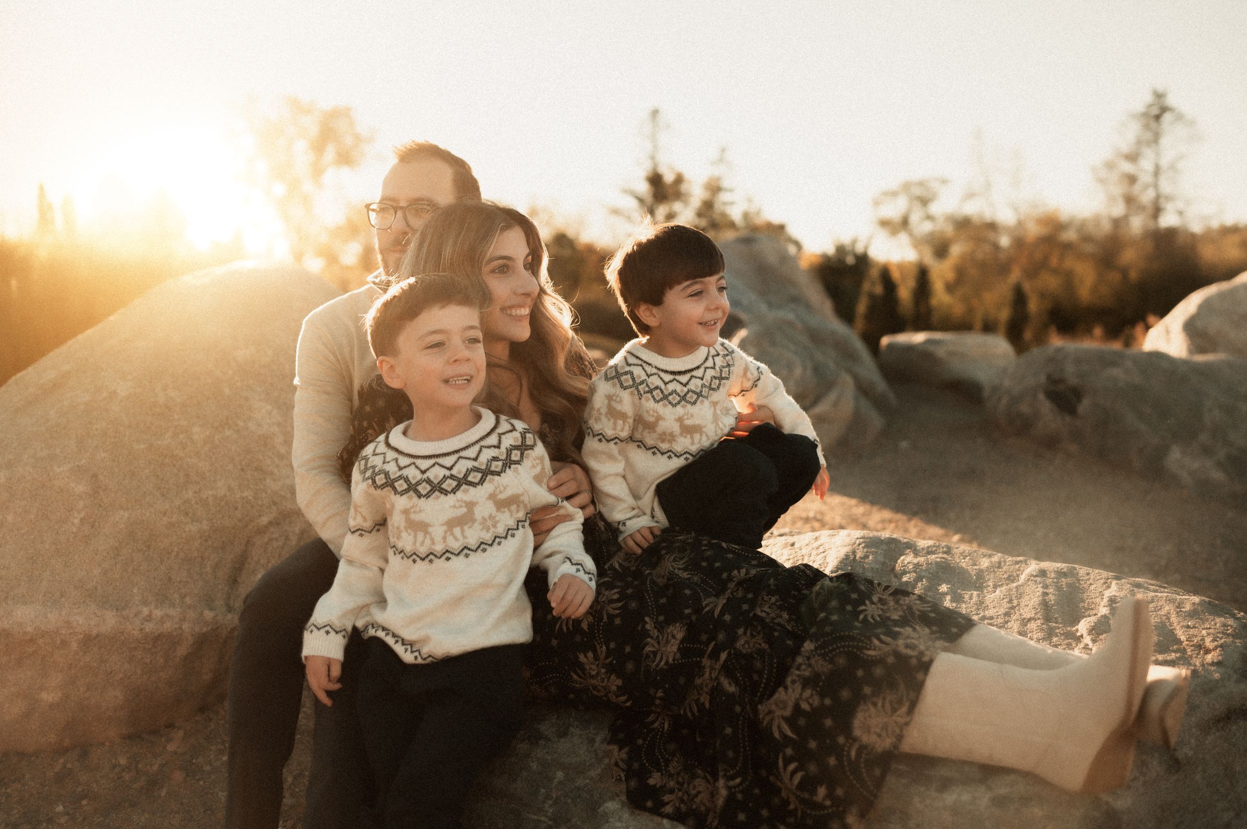 A parent holds a small child wrapped in a plaid blanket during golden hour.