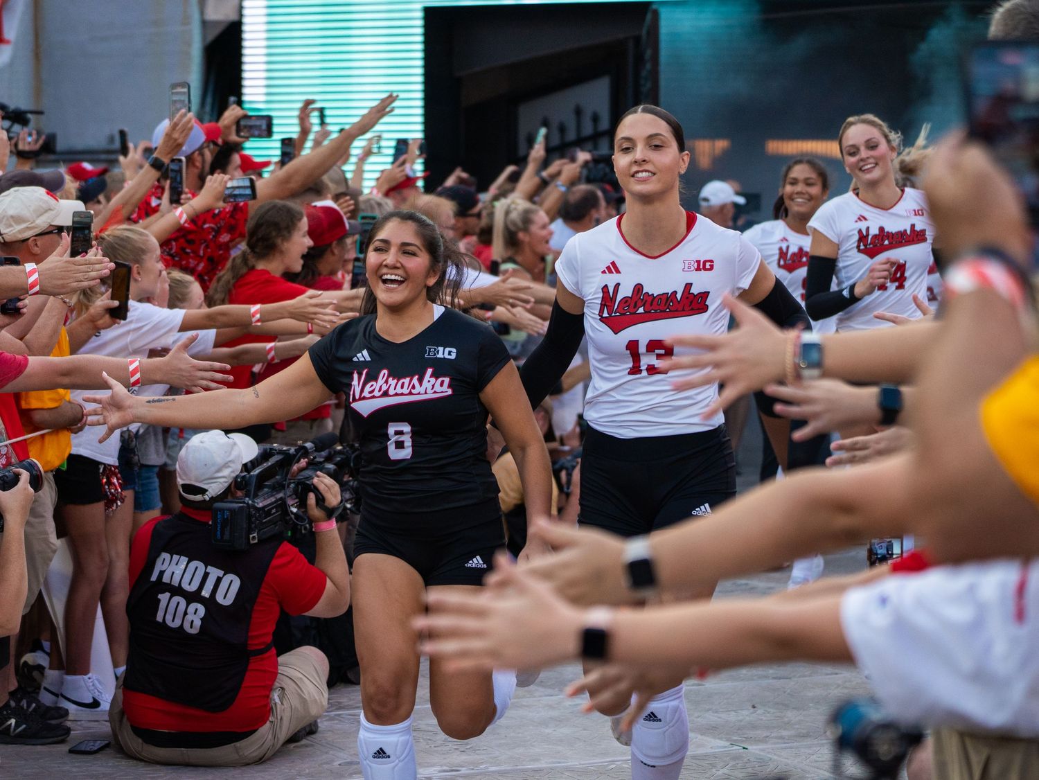Athletes interact with cheering fans in a packed stadium during a sporting event.