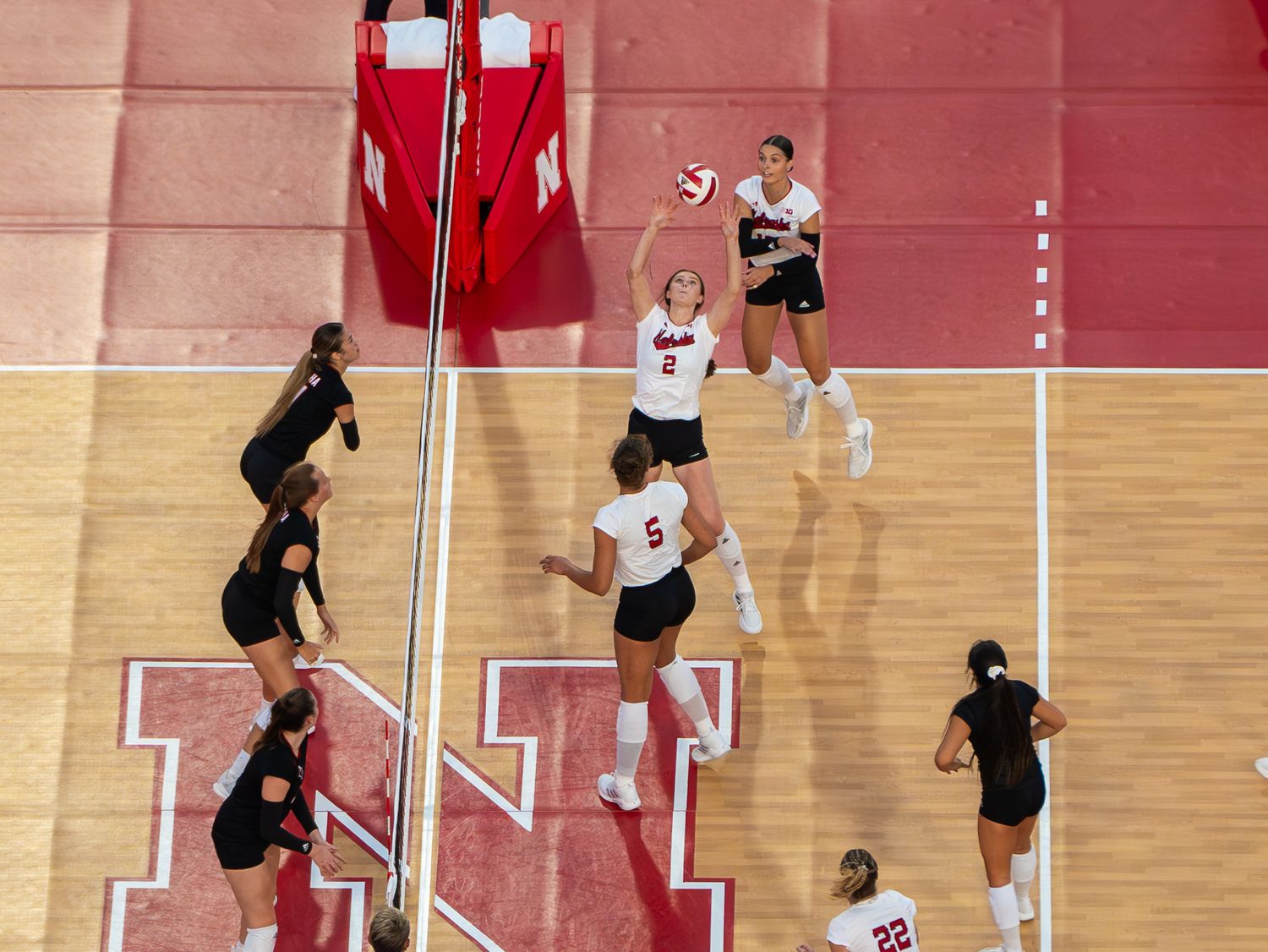 Aerial view of volleyball match showing players positioned around the net during gameplay.