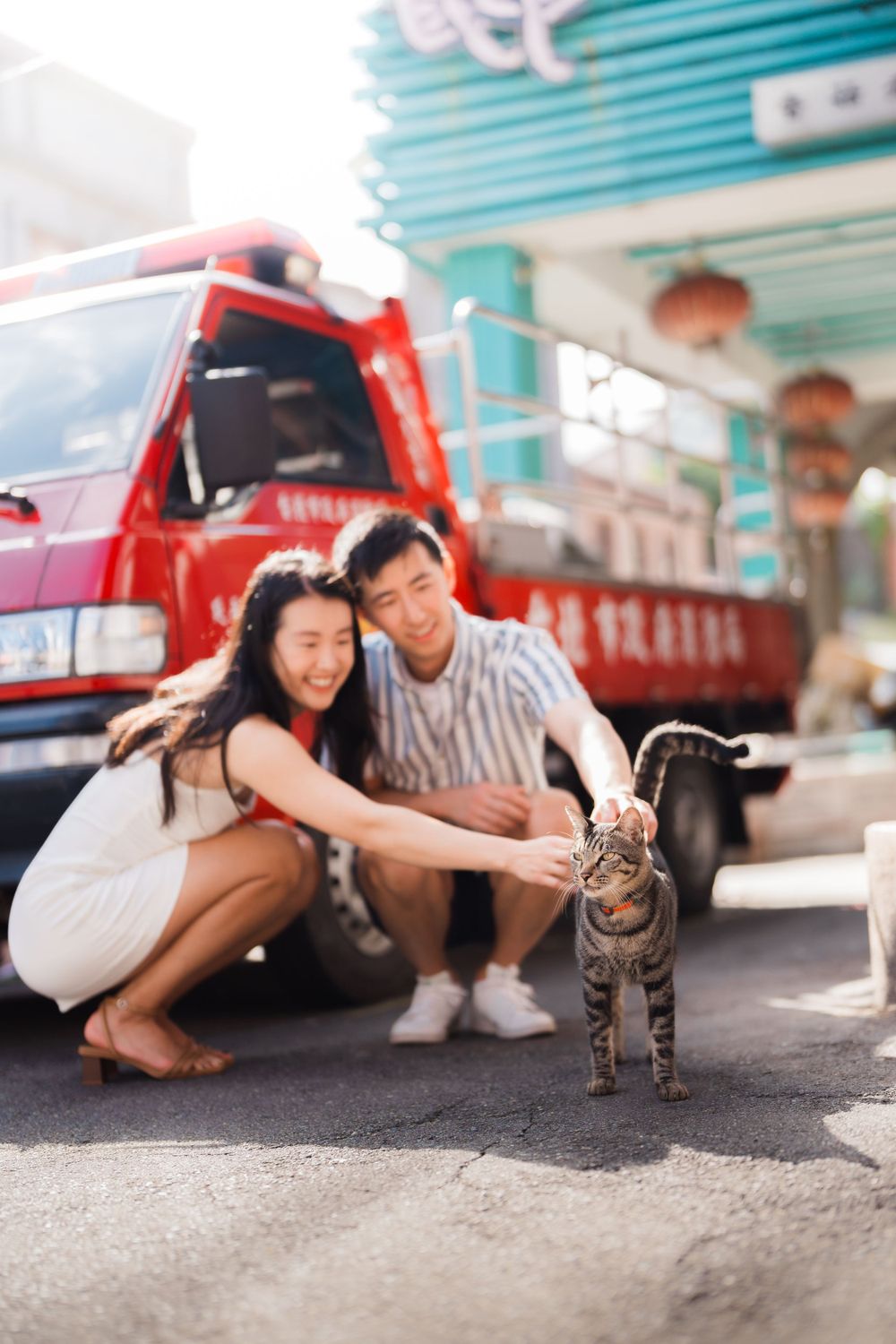 A couple petting a cat next to the fire truck at Dihua Street in Dadaocheng in Taipei City.