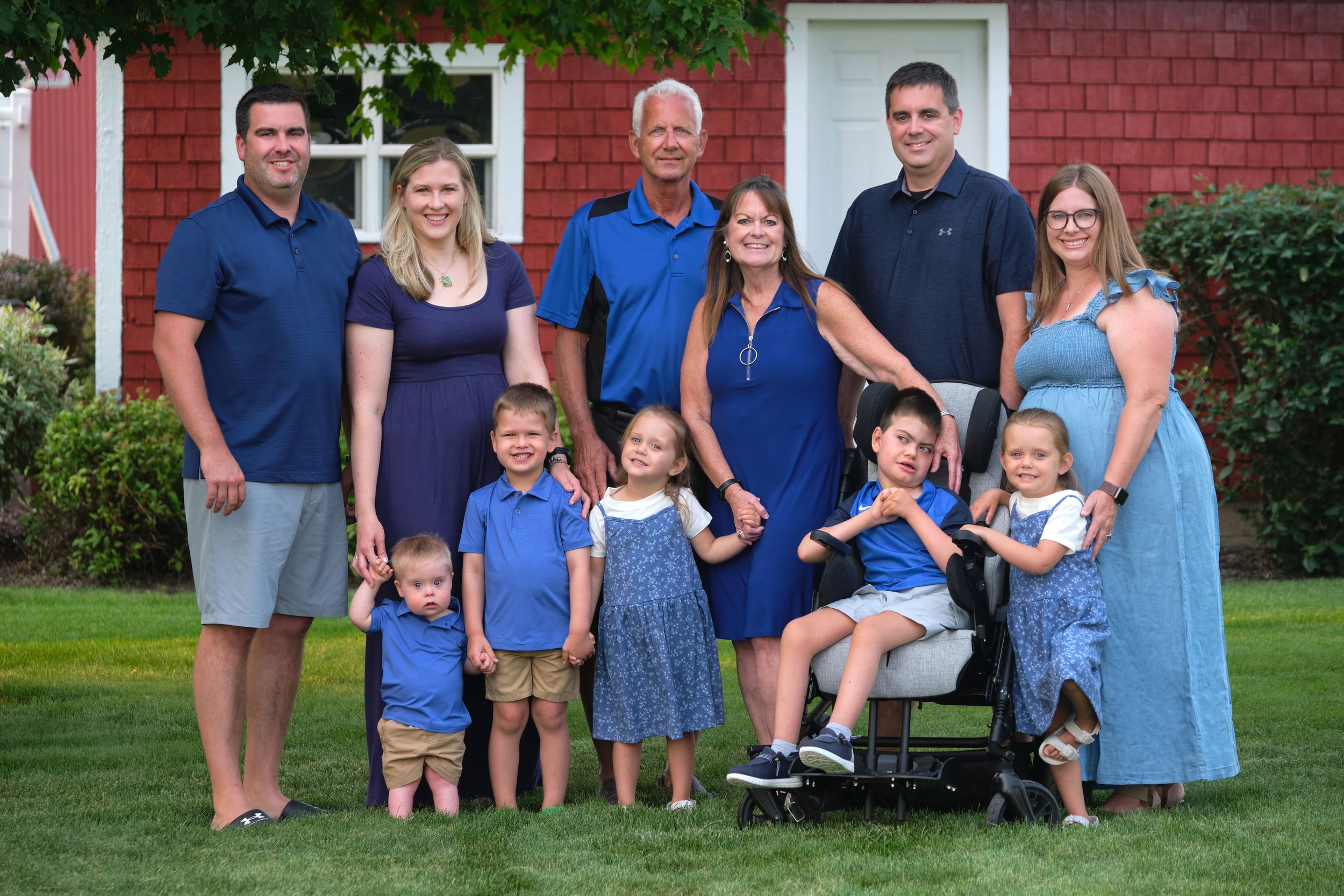 A family of 11 stands in their backyard for a family photo.